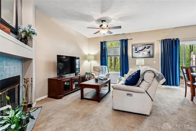 living area featuring carpet floors, a ceiling fan, a fireplace, and baseboards