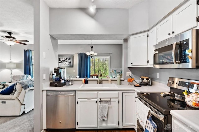 kitchen with stainless steel appliances, a sink, white cabinetry, a ceiling fan, and light countertops