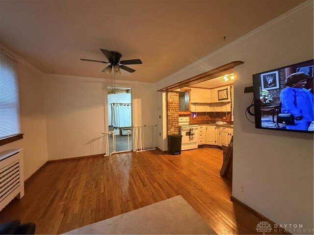 2 Brompton Ln, Cincinnati, OH 45218 - unfurnished living room featuring light wood-style flooring, ceiling fan, radiator heating unit, and ornamental molding