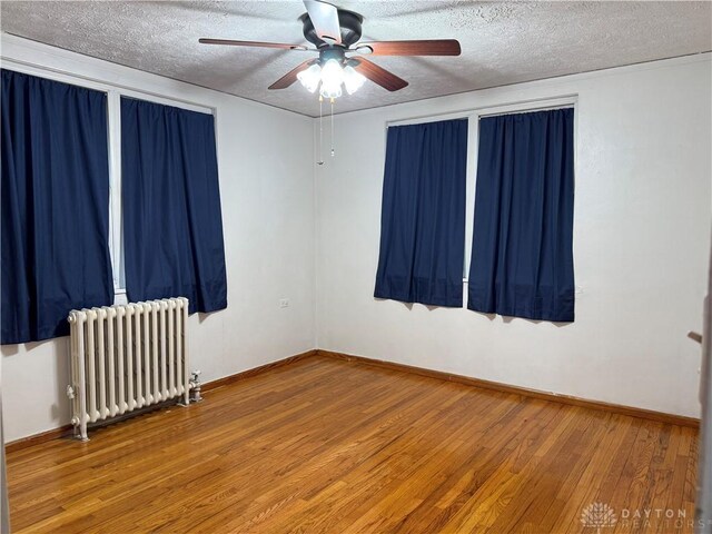 2 Brompton Ln, Cincinnati, OH 45218 - empty room with radiator heating unit, a textured ceiling, wood-type flooring, and ceiling fan