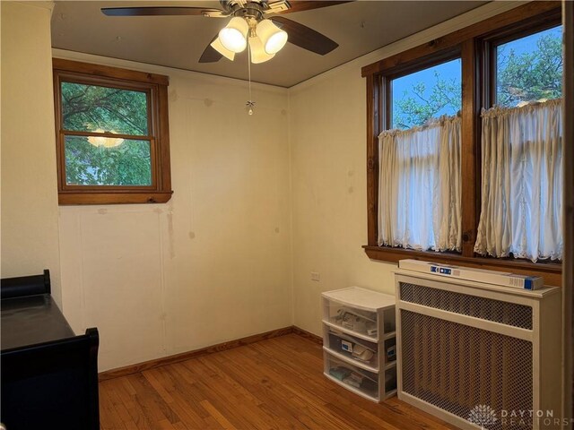 2 Brompton Ln, Cincinnati, OH 45218 - unfurnished bedroom featuring light wood-style flooring, multiple windows, radiator heating unit, and ceiling fan