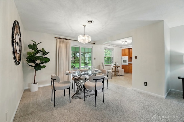 dining area featuring light carpet, a chandelier, and baseboards