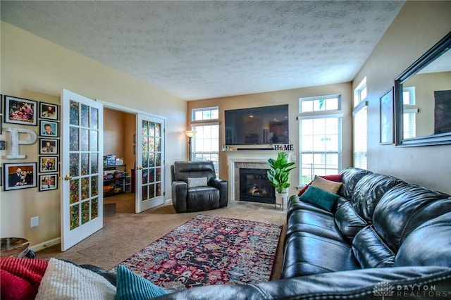 living area with french doors, carpet, a glass covered fireplace, a textured ceiling, and baseboards