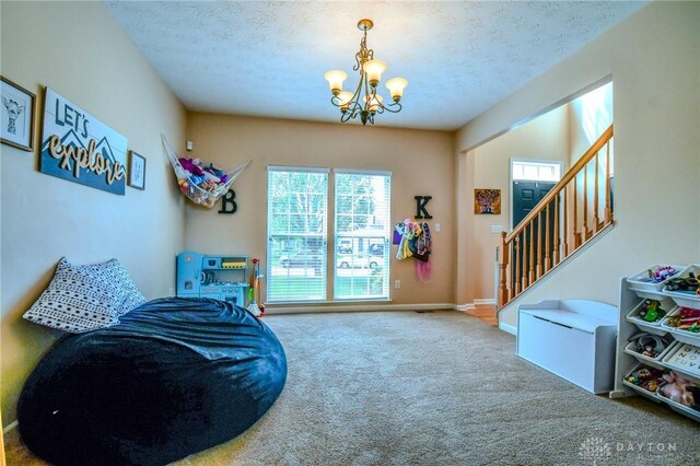 living area featuring carpet flooring, a chandelier, stairway, a textured ceiling, and baseboards