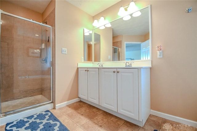bathroom featuring a shower stall, baseboards, tile patterned flooring, and double vanity