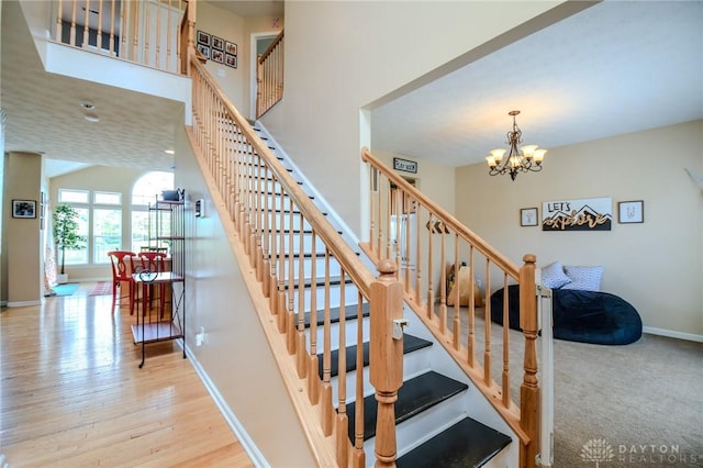 stairs featuring a chandelier, baseboards, and wood finished floors