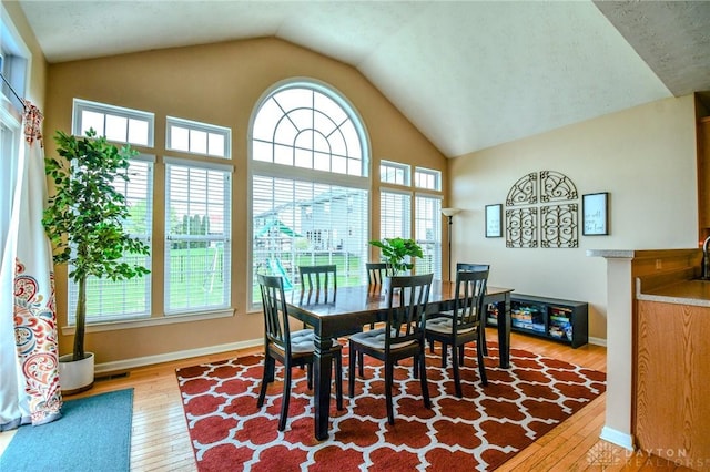 dining area with wood-type flooring, vaulted ceiling, and baseboards