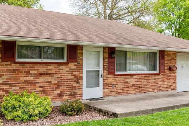 3762 Waterbury Dr, Kettering, OH 45439 - property entrance with brick siding, an attached garage, and a shingled roof