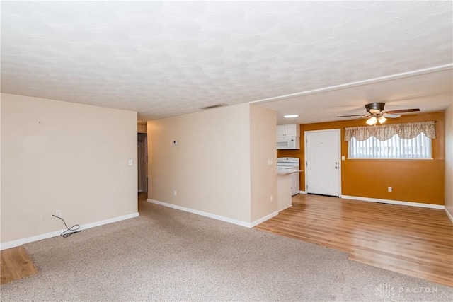 3762 Waterbury Dr, Kettering, OH 45439 - unfurnished living room featuring ceiling fan, baseboards, light colored carpet, and light wood-style floors