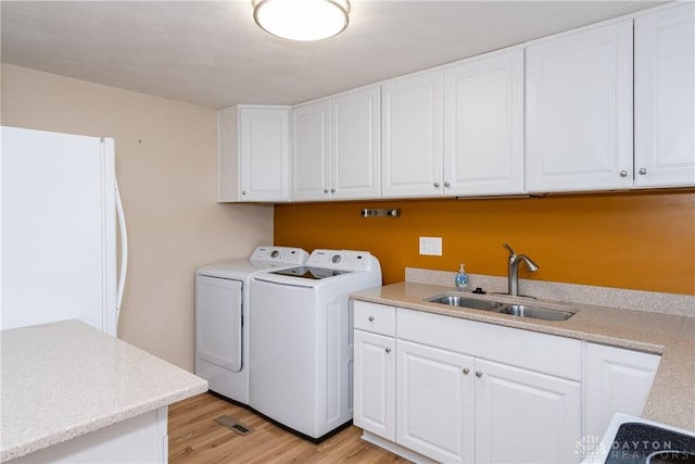 3762 Waterbury Dr, Kettering, OH 45439 - laundry area with washing machine and dryer, light wood-style flooring, and cabinet space