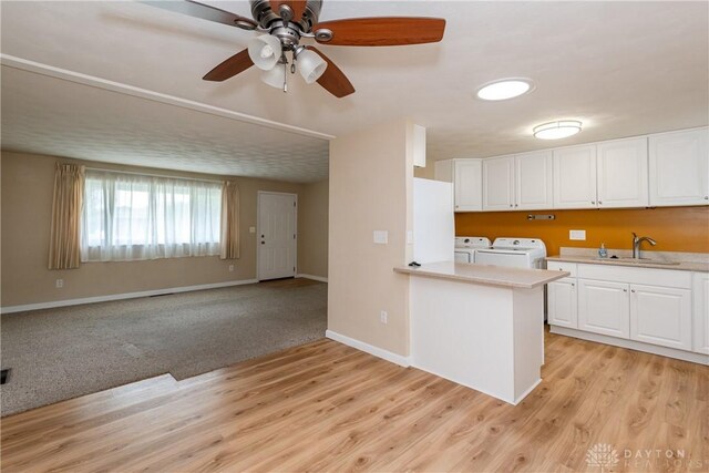 3762 Waterbury Dr, Kettering, OH 45439 - kitchen with independent washer and dryer, light countertops, white cabinetry, a sink, and light wood-style floors