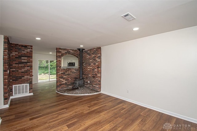 unfurnished living room with wood finished floors, baseboards, a wood stove, and recessed lighting