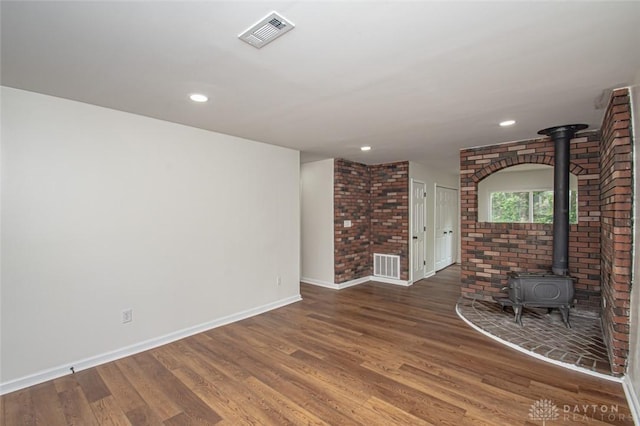 unfurnished living room featuring a wood stove, baseboards, wood finished floors, and recessed lighting