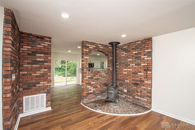 unfurnished living room featuring wood finished floors, baseboards, a wood stove, and recessed lighting