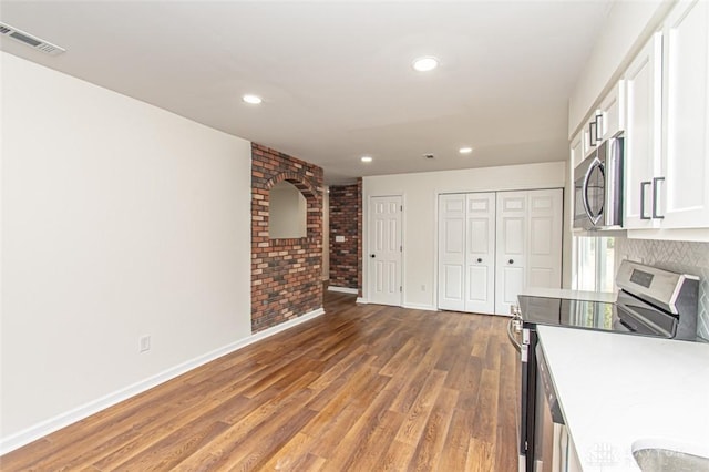 kitchen featuring stainless steel appliances, white cabinets, baseboards, wood finished floors, and recessed lighting