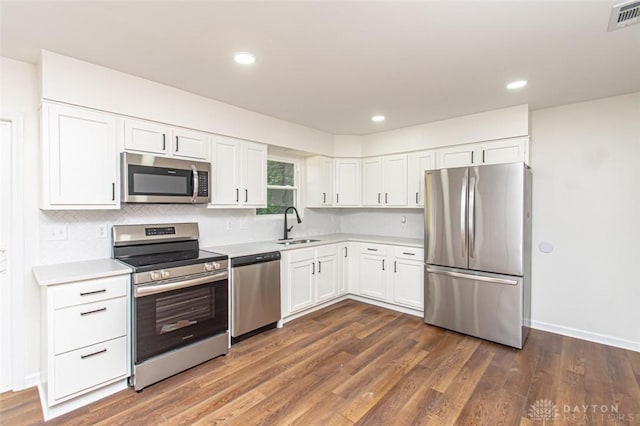 kitchen featuring appliances with stainless steel finishes, a sink, light countertops, white cabinets, and dark wood finished floors