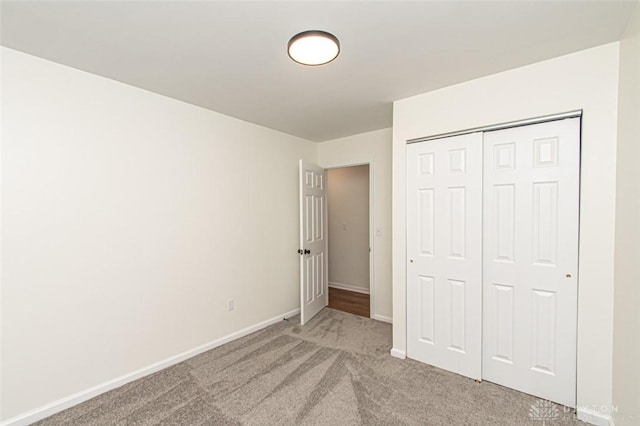 unfurnished bedroom featuring light carpet, baseboards, and a closet