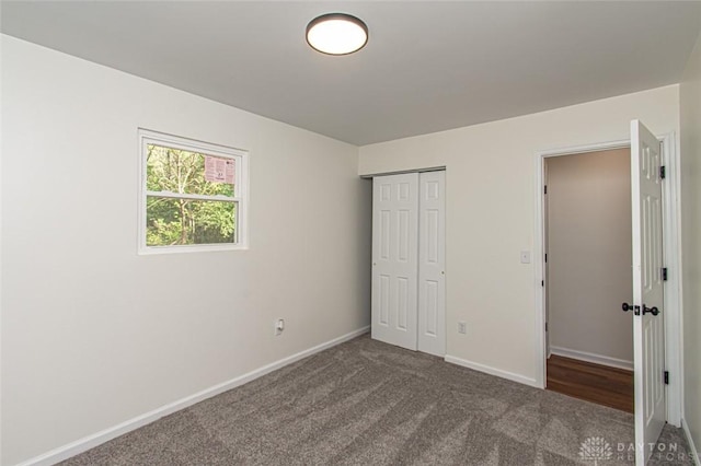 unfurnished bedroom with carpet floors, baseboards, and a closet