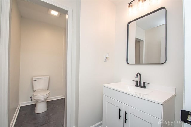 half bath with baseboards, vanity, toilet, and tile patterned floors