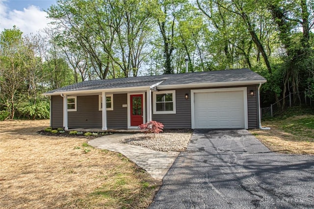 ranch-style home featuring a garage, covered porch, and asphalt driveway