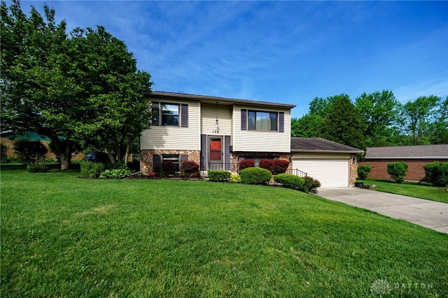 raised ranch featuring brick siding, concrete driveway, a front yard, and a garage