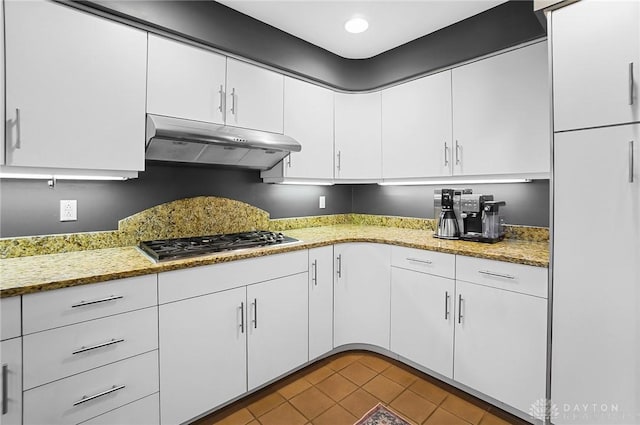 1900 Kresswood Cir, Kettering, OH 45429 - kitchen with under cabinet range hood, stainless steel gas stovetop, white cabinetry, tile patterned flooring, and light stone countertops