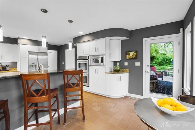 1900 Kresswood Cir, Kettering, OH 45429 - kitchen with appliances with stainless steel finishes, a breakfast bar area, white cabinets, pendant lighting, and light tile patterned floors