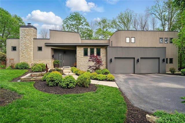 1900 Kresswood Cir, Kettering, OH 45429 - view of front of house with an attached garage, asphalt driveway, a chimney, a front lawn, and stone siding