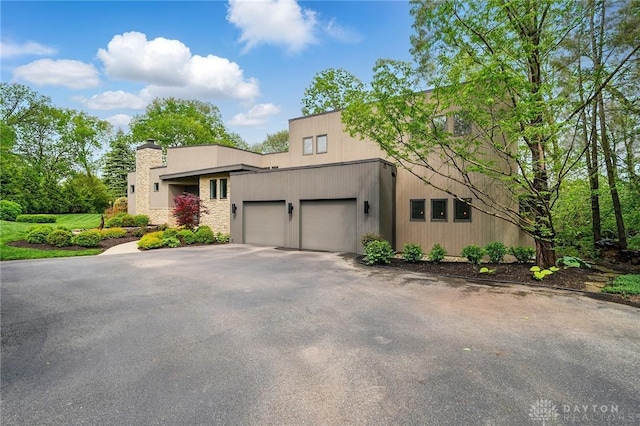 1900 Kresswood Cir, Kettering, OH 45429 - view of side of property with a garage, asphalt driveway, and a chimney