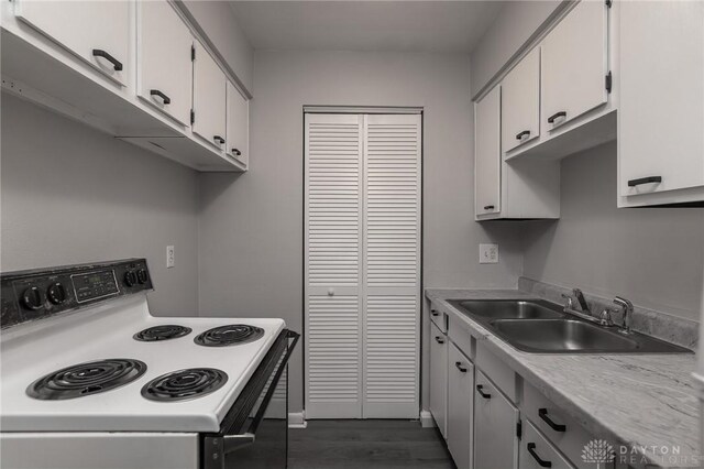 2525 Germantown St, Dayton, OH 45417 - kitchen with range with electric stovetop, a sink, light countertops, white cabinetry, and dark wood-type flooring