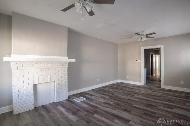 unfurnished living room with a ceiling fan, dark wood-style flooring, and a brick fireplace