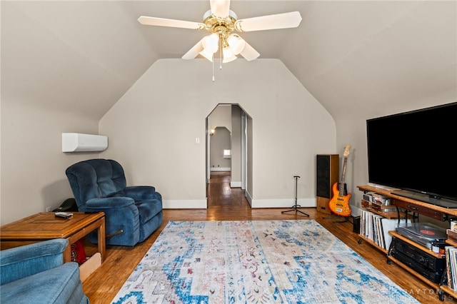 654 S Market St, Troy, OH 45373 - living room with vaulted ceiling, ceiling fan, a wall unit AC, arched walkways, and wood finished floors