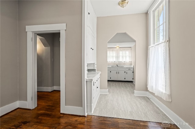 654 S Market St, Troy, OH 45373 - hallway with wood finished floors, baseboards, arched walkways, and a sink