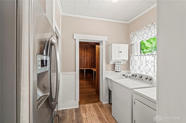 654 S Market St, Troy, OH 45373 - laundry room featuring washing machine and clothes dryer, light wood-type flooring, ornamental molding, cabinet space, and a wainscoted wall