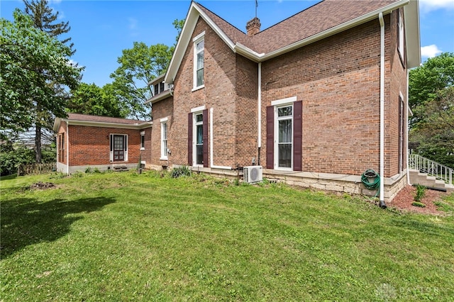 654 S Market St, Troy, OH 45373 - rear view of house with brick siding, a lawn, a cooling unit, and a chimney
