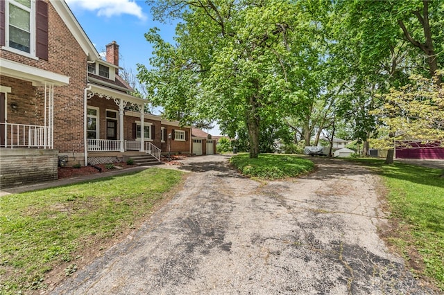 654 S Market St, Troy, OH 45373 - view of grassy yard featuring a porch, asphalt driveway, and a garage