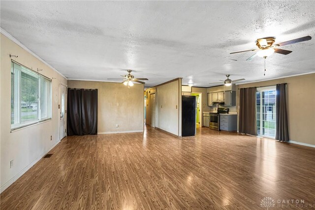 unfurnished living room featuring a ceiling fan, a textured ceiling, dark wood-style flooring, baseboards, and crown molding