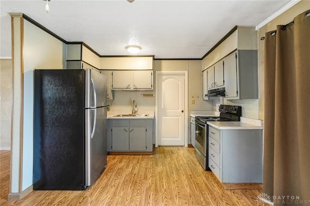 kitchen featuring stainless steel appliances, gray cabinets, light wood-style floors, light countertops, and crown molding