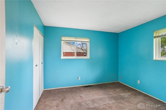 carpeted empty room featuring baseboards