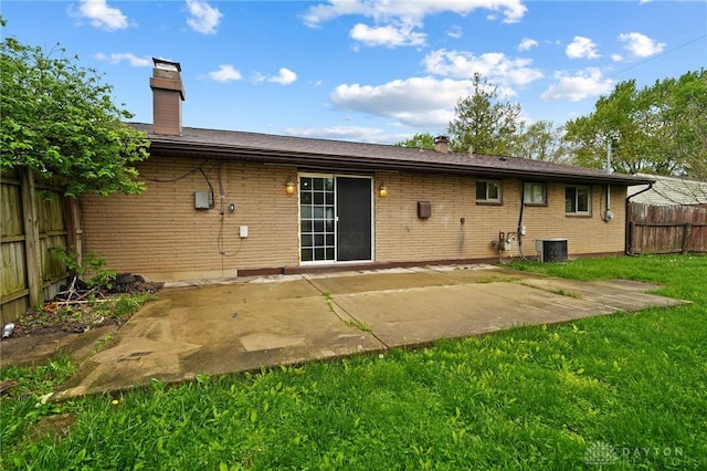 back of property with a chimney, brick siding, a patio area, and cooling unit