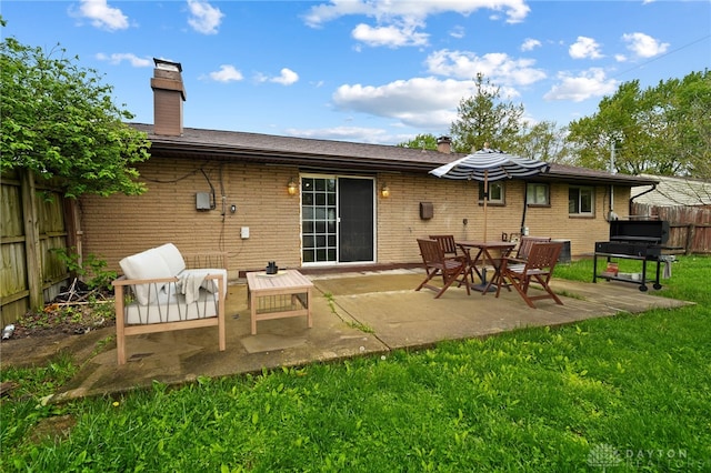 rear view of house featuring a chimney, brick siding, and a patio area