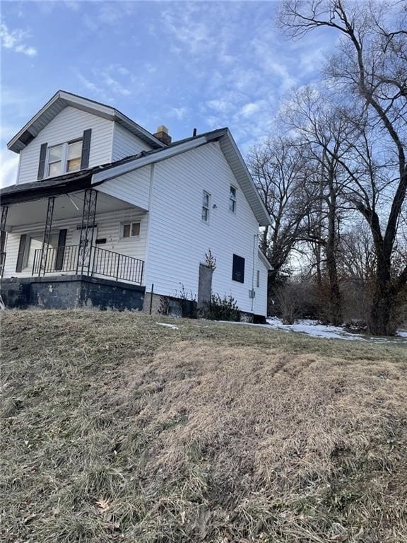 view of home's exterior featuring a chimney and covered porch