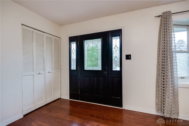 entrance foyer with dark wood-style flooring and baseboards