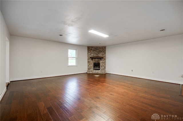 unfurnished living room featuring dark wood-type flooring, baseboards, and a fireplace