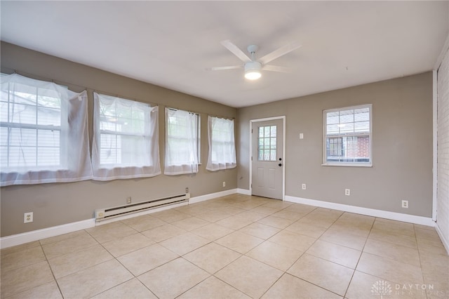 empty room featuring a baseboard heating unit, ceiling fan, light tile patterned floors, and baseboards
