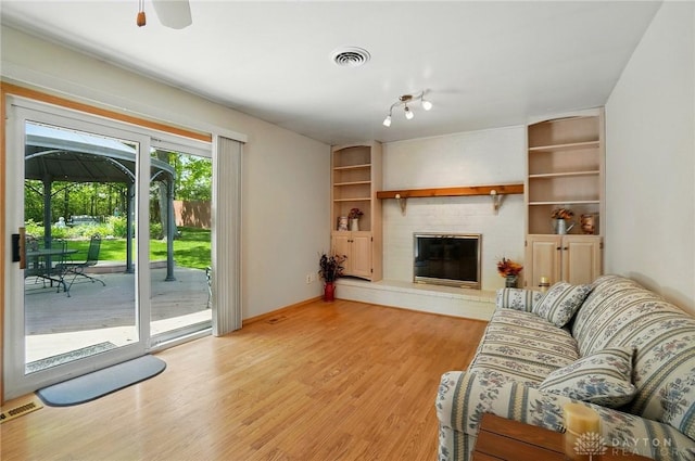 3352 Morning Glory Rd, Dayton, OH 45449 - living area with a brick fireplace, light wood finished floors, built in shelves, and a ceiling fan
