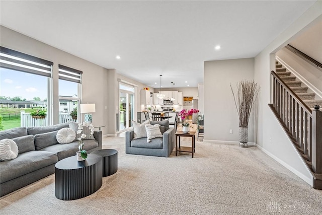 living area featuring stairs, baseboards, recessed lighting, and light colored carpet