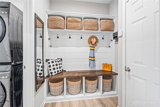 mudroom with stacked washing machine and dryer and wood finished floors