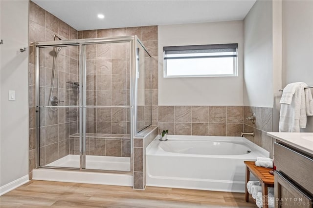 full bath with vanity, a shower stall, a garden tub, and wood finished floors