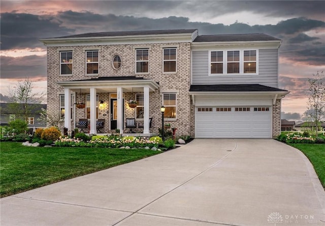 1239 Champion Way, Washington Twp, OH 45458 - view of front of house featuring a lawn, an attached garage, brick siding, and covered porch